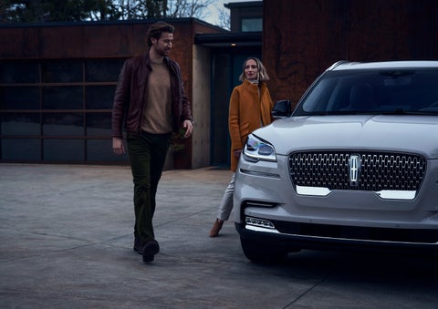 A man and a woman approaching a 2024 Lincoln Aviator® SUV, which illuminates certain lights when they are close | Gray-Daniels Lincoln in Brandon MS
