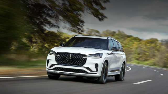 A white 2025 Lincoln Aviator® SUV is being driven down a road lined with trees. | Gray-Daniels Lincoln in Brandon MS