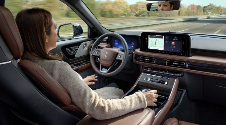 A 2026 Lincoln Aviator® SUV is being driven hands-free on a highway near a forest | Gray-Daniels Lincoln in Brandon MS