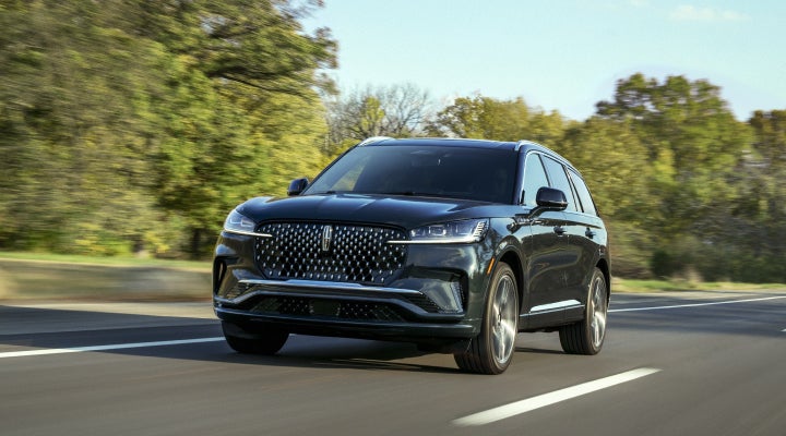 A 2026 Lincoln Black Label™ Aviator® SUV is being driven down a road lined with trees. | Gray-Daniels Lincoln in Brandon MS