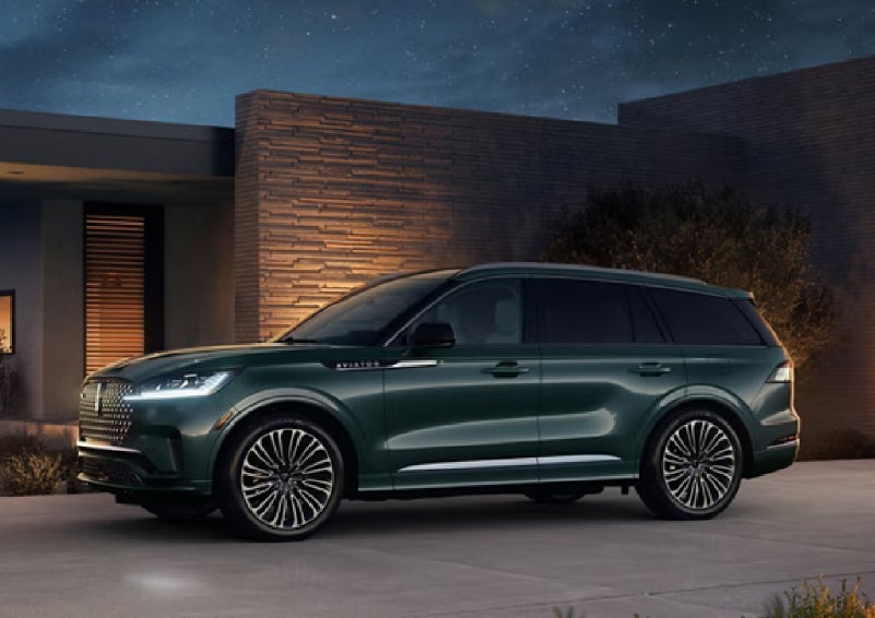 A green 2027 Lincoln Aviator® SUV is parked outside a contemporary home. | Gray-Daniels Lincoln in Brandon MS