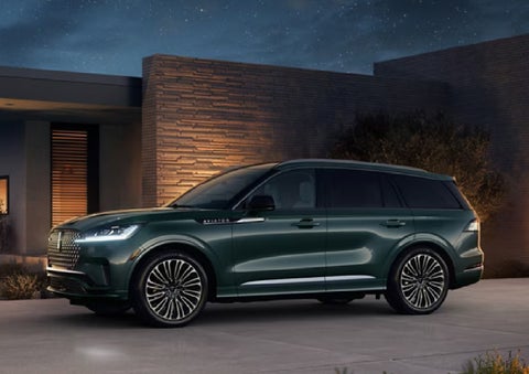 A green 2027 Lincoln Aviator® SUV is parked outside a contemporary home. | Gray-Daniels Lincoln in Brandon MS