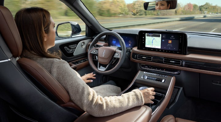 A 2027 Lincoln Aviator® SUV is being driven hands-free on a highway lined with trees. | Gray-Daniels Lincoln in Brandon MS