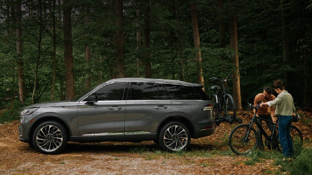 A father and son load e-bikes on a bike rack attached to a 2027 Lincoln Aviator® SUV. | Gray-Daniels Lincoln in Brandon MS