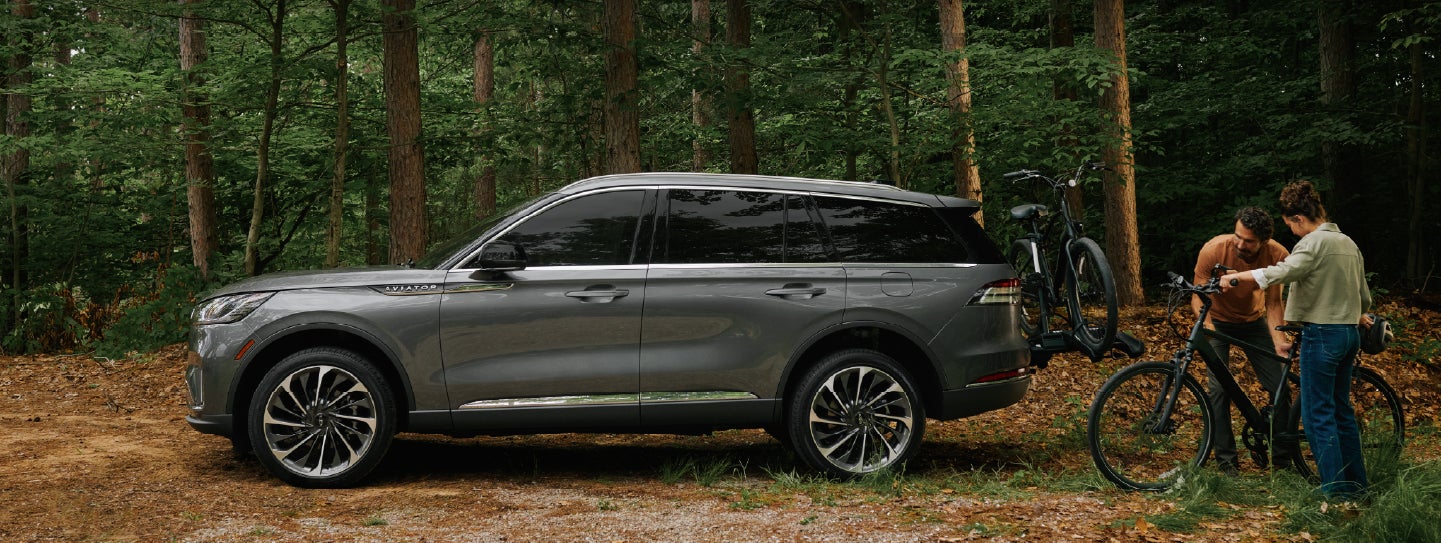 A father and son load e-bikes on a bike rack attached to a 2027 Lincoln Aviator® SUV. | Gray-Daniels Lincoln in Brandon MS